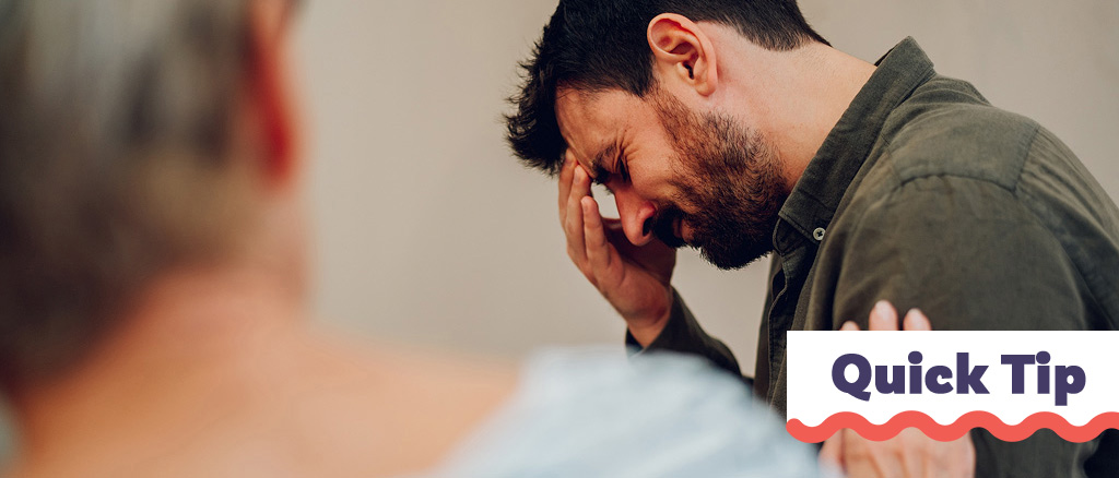A man shows emotion or pain while a woman supports him.